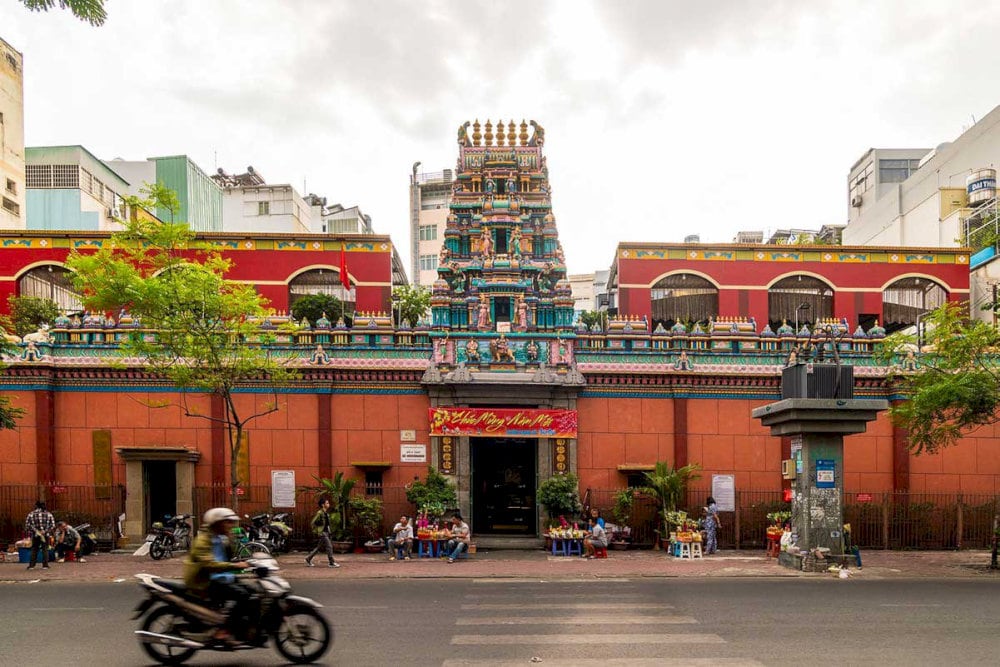 Visitors entering the temple gate, gazing at the radiant Gopuram as if stepping into a spiritual realm